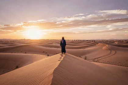 Paysage désertique du Sahara marocain à Merzouga au lever du soleil avec dunes dorées et silhouette berbère