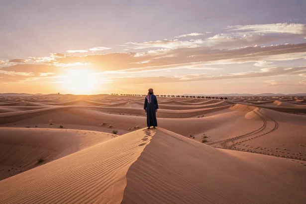 Paysage désertique du Sahara marocain à Merzouga au lever du soleil avec dunes dorées et silhouette berbère